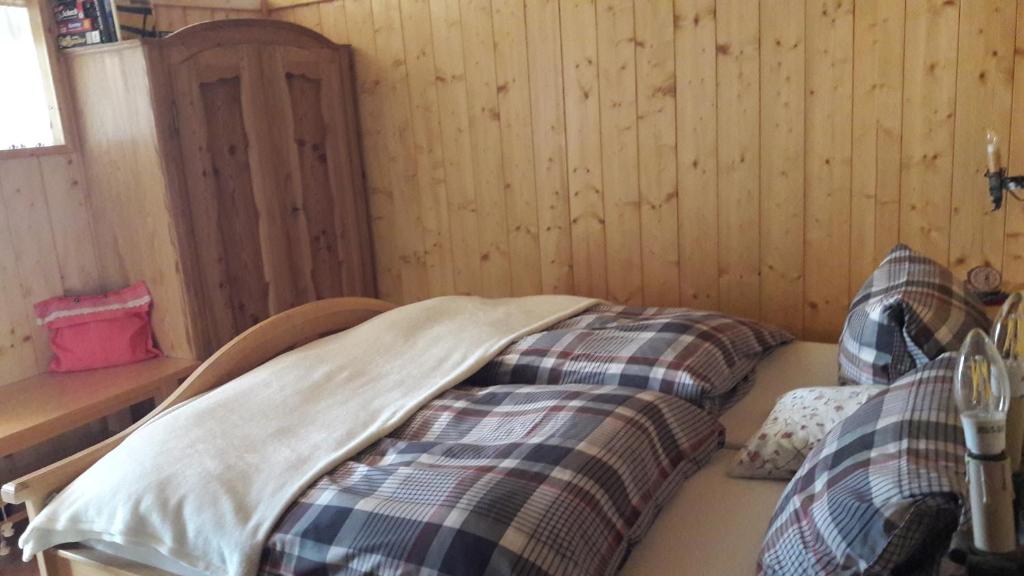 Cama en habitación con paredes de madera en Gartenwohnung auf der Sommeralm en Sankt Kathrein am Offenegg