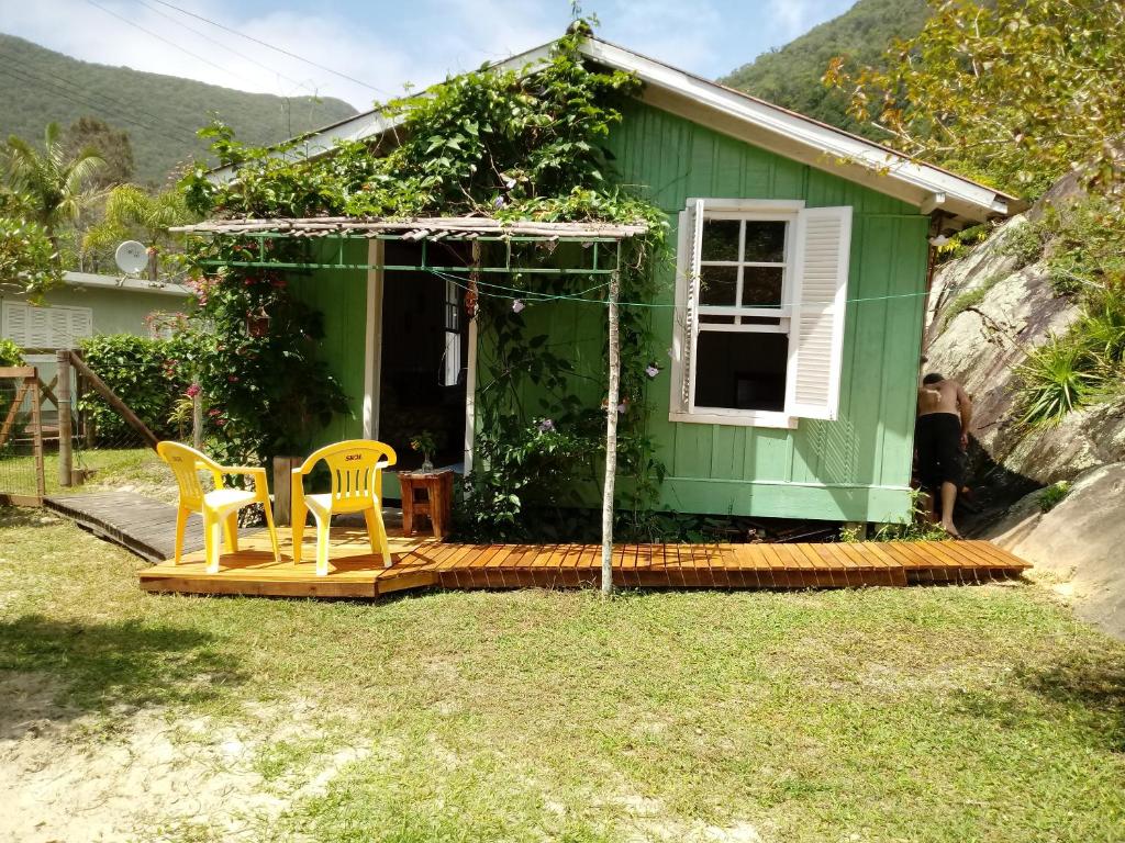 a green house with two yellow chairs in front of it at Casa na Praia do Matadeiro in Florianópolis