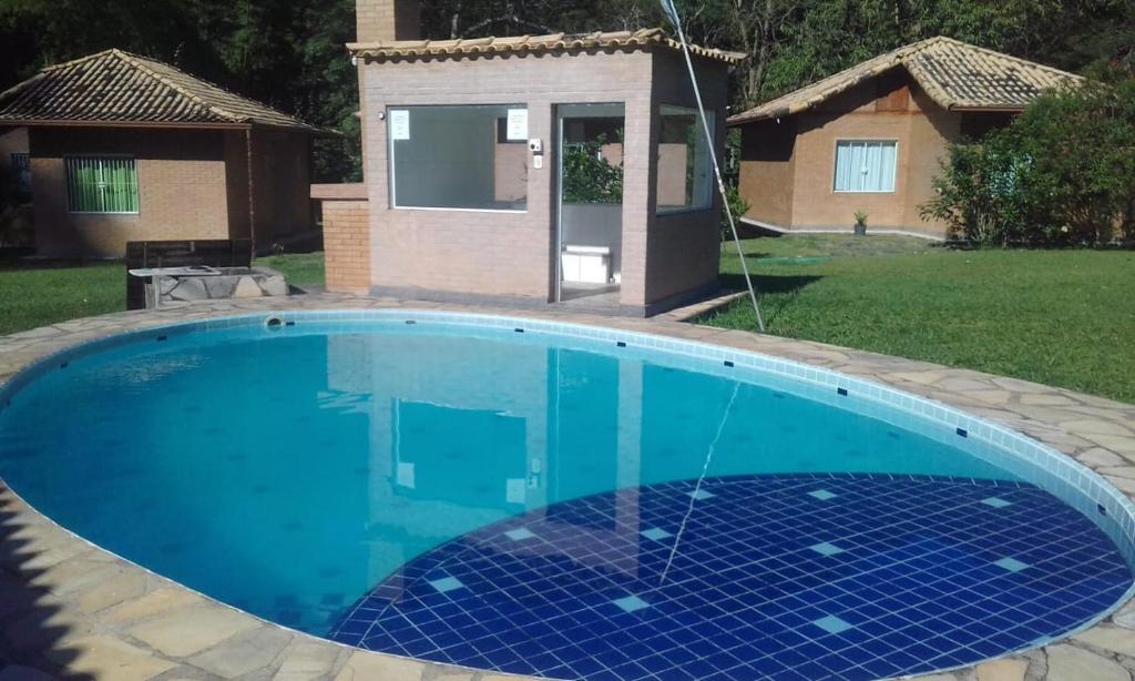 a blue swimming pool with a house in the background at Recanto da natureza in Sana