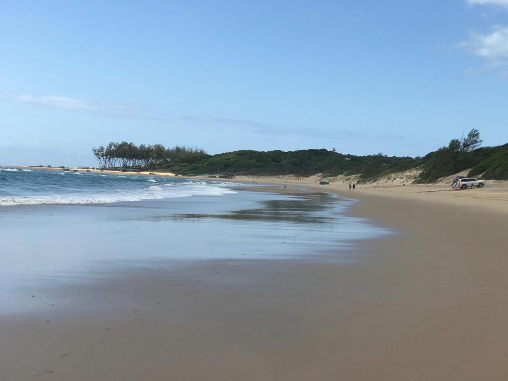 a beach with people walking on the sand and the ocean at Sodwana Bay Lodge House 34 in Sodwana Bay