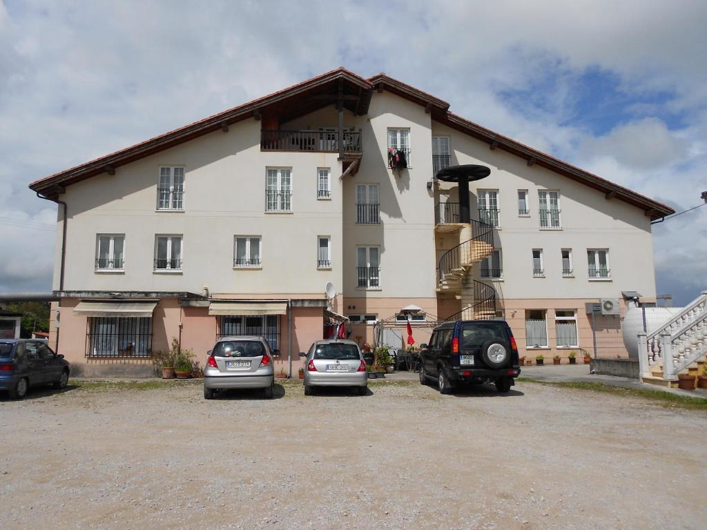 ein großes Gebäude mit Autos auf einem Parkplatz in der Unterkunft Hotel Narcea in Valles