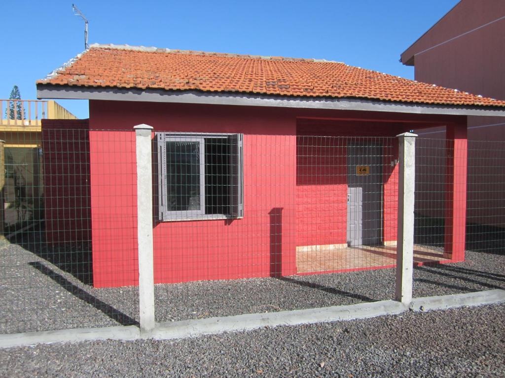 a red building with a fence in front of it at Oasis Sul Tramandaí Casa Vermelha in Tramandaí