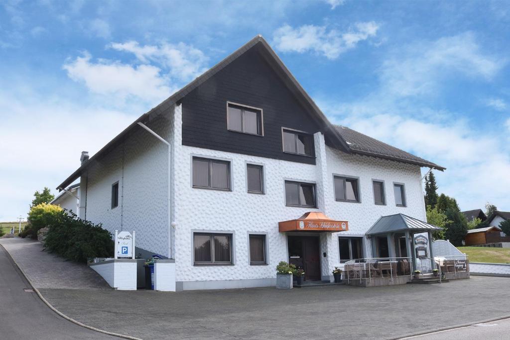 un grand bâtiment blanc avec un toit noir dans l'établissement Haus Schieferstein, à Dahlem