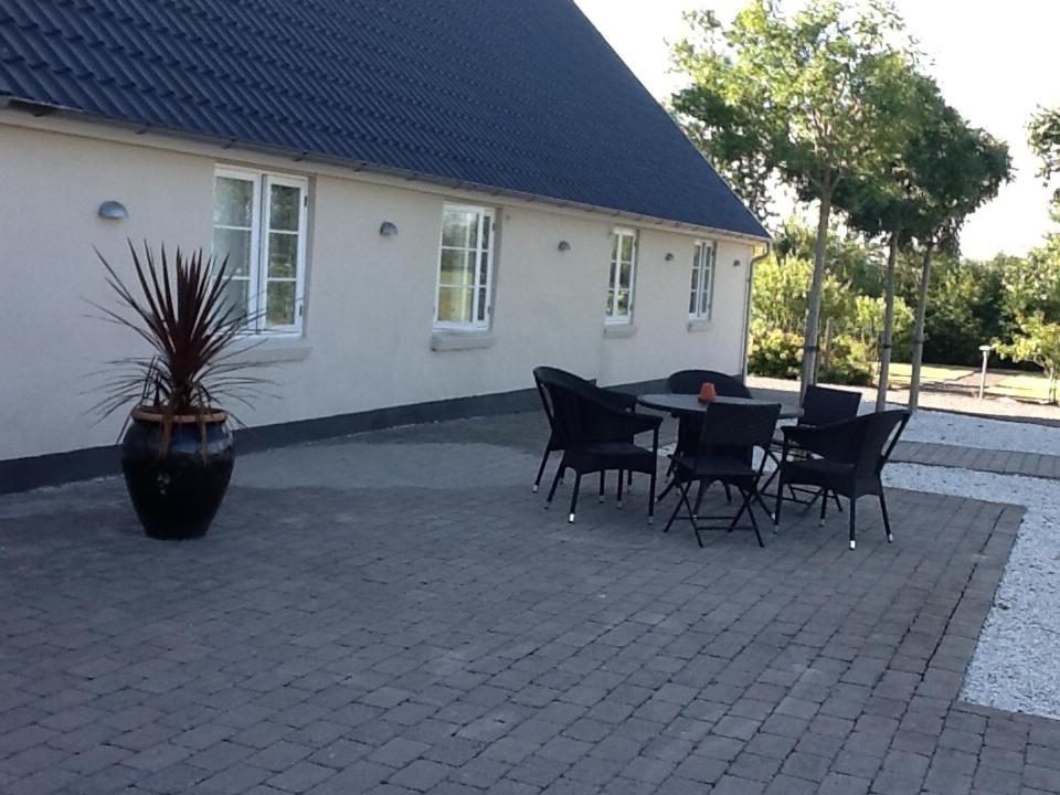 a patio with a table and chairs in front of a house at Lykkebjerg in Varde