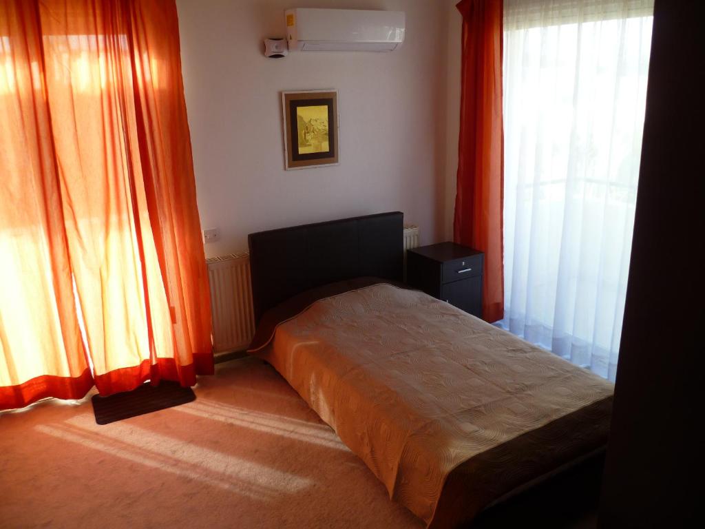 a bedroom with a bed with orange curtains at Private deluxe room with balcony at Datacom building in Nicosia