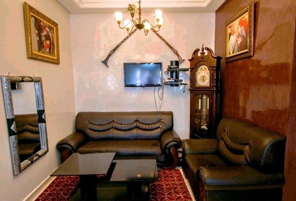 a living room with a couch and a table and a clock at Salam Appartement Agadir in Agadir