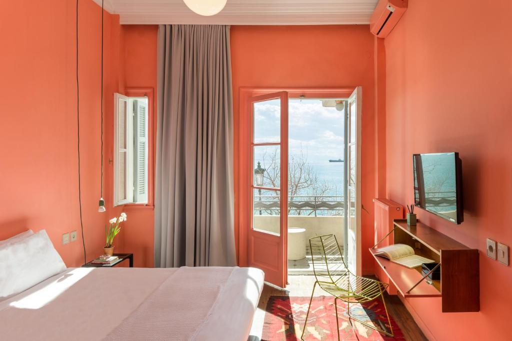 1 dormitorio con paredes de color naranja, 1 cama y TV en AiR Waterfront Nikis Apartment, en Tesalónica
