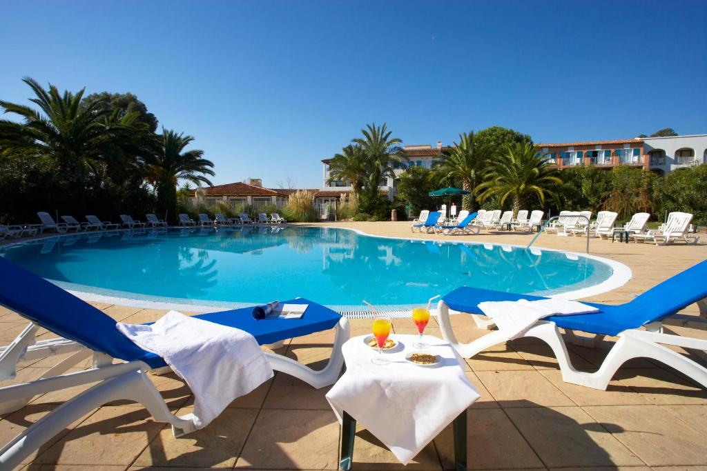 グリモーにあるSOWELL HOTELS Saint Tropezのラウンジチェアとドリンク付きのテーブルが備わるプールを併設しています。