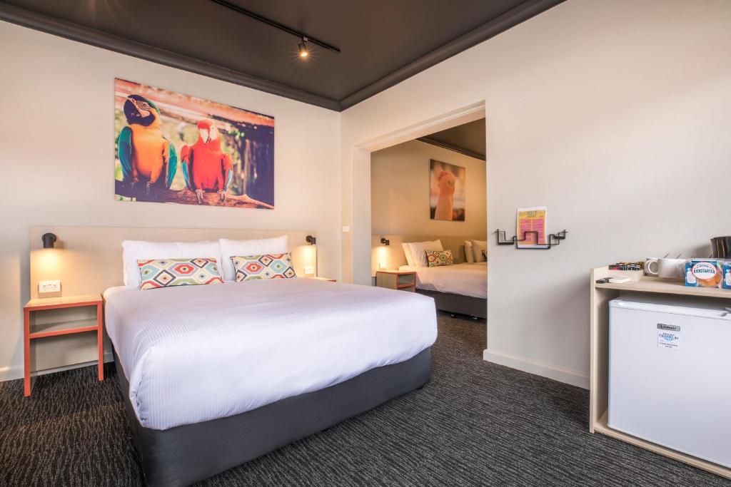 a hotel room with a large bed and a tv at Nightcap at Chester Hill Hotel in Bankstown