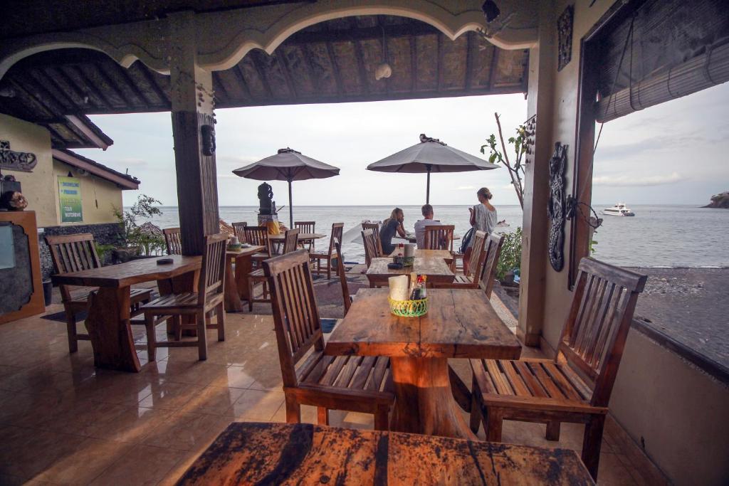 - un restaurant avec des tables et des chaises et une vue sur l'océan dans l'établissement Sunrise Cafe Bungalows, à Amed