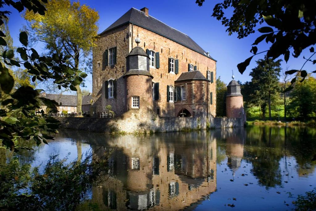 um velho castelo com o seu reflexo na água em Fletcher Hotel-Restaurant Kasteel Erenstein em Kerkrade