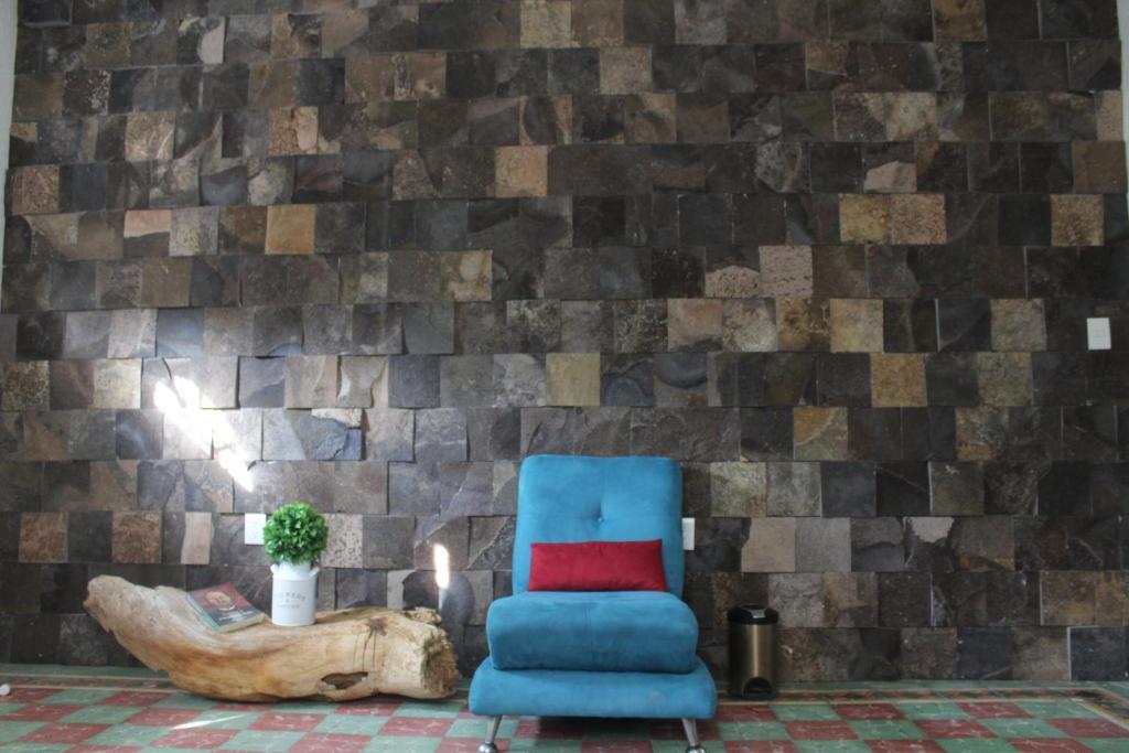 une chaise bleue dans une chambre dotée d'un mur en pierre dans l'établissement Casa en el centro de veracruz, à Veracruz