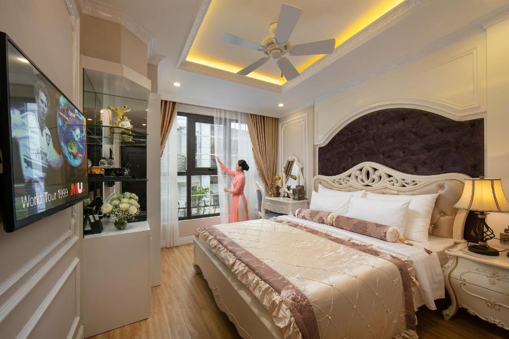 a woman standing in a bedroom looking out the window at Royal Holiday Hanoi Hotel in Hanoi