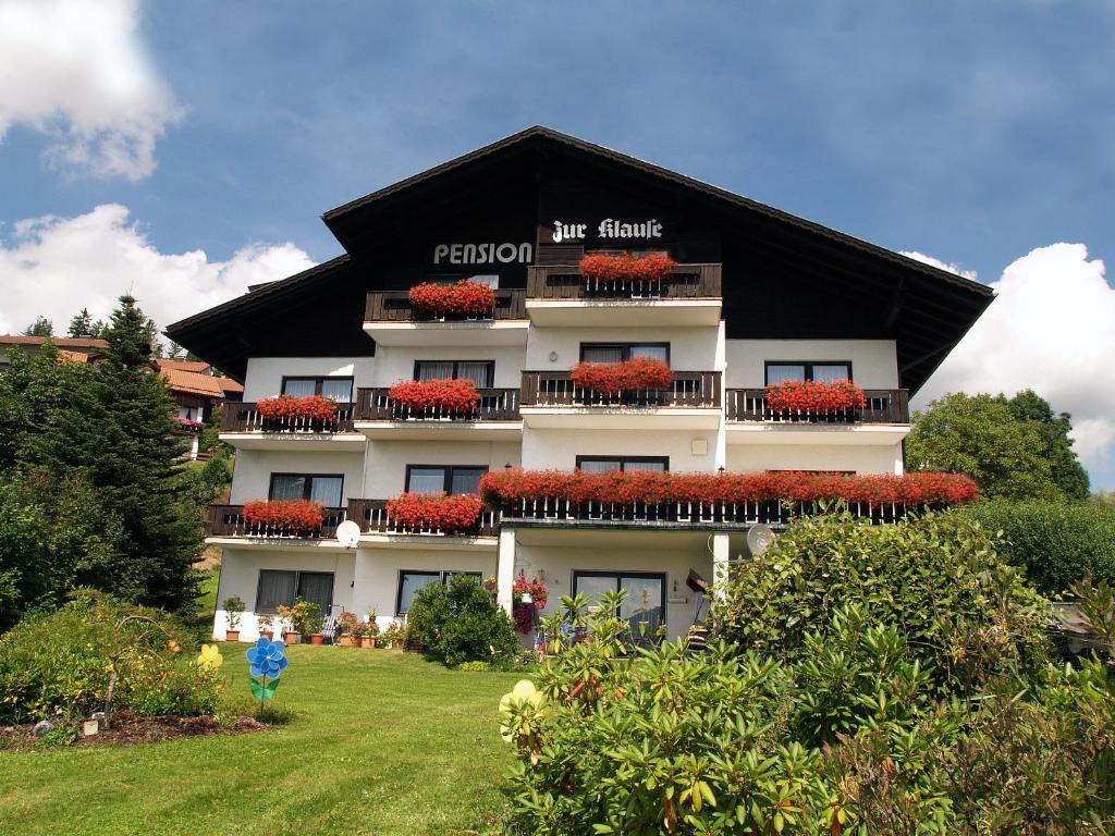 a large white building with red flowers on it at Pension zur Klause in Bodenmais