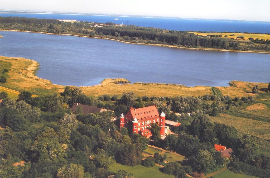 eine Luftansicht eines Hauses auf einem Hügel neben einem See in der Unterkunft Hotel Schloss Spyker in Glowe