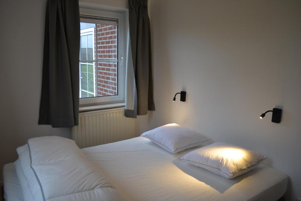 a bed with two pillows and a window in a room at Vue d'en Haut in Durbuy