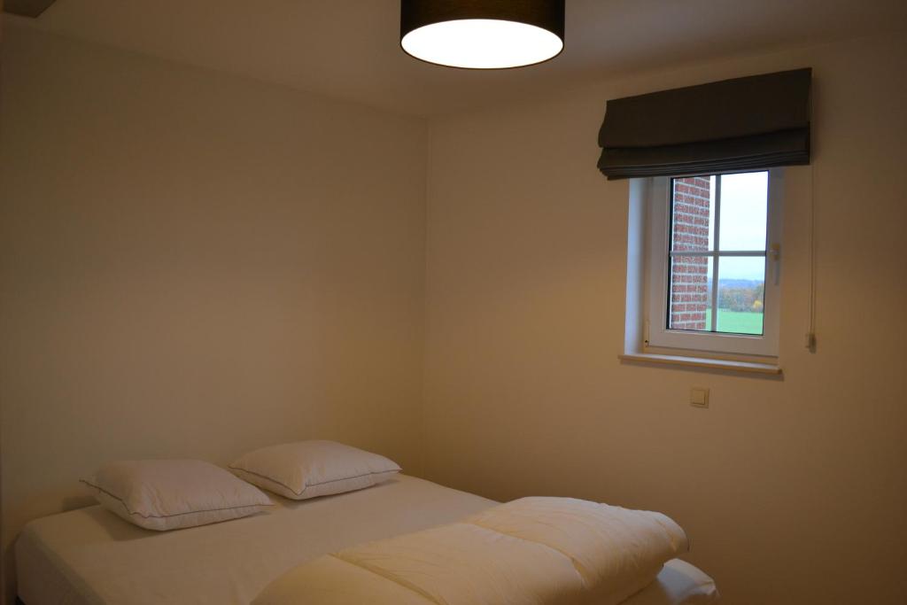 a bedroom with a bed with two pillows and a window at Vue d'en Haut in Durbuy