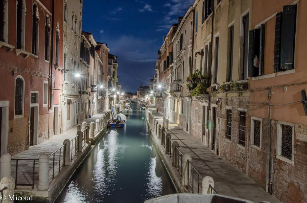 a canal in a city at night with a boat at Luxury Venetian Rooms in Venice