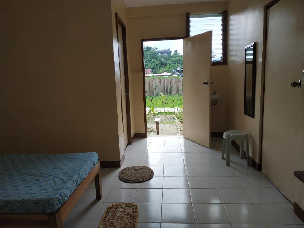 a room with a bed and a door with a window at Nelmann's Nipa Huts in San Vicente