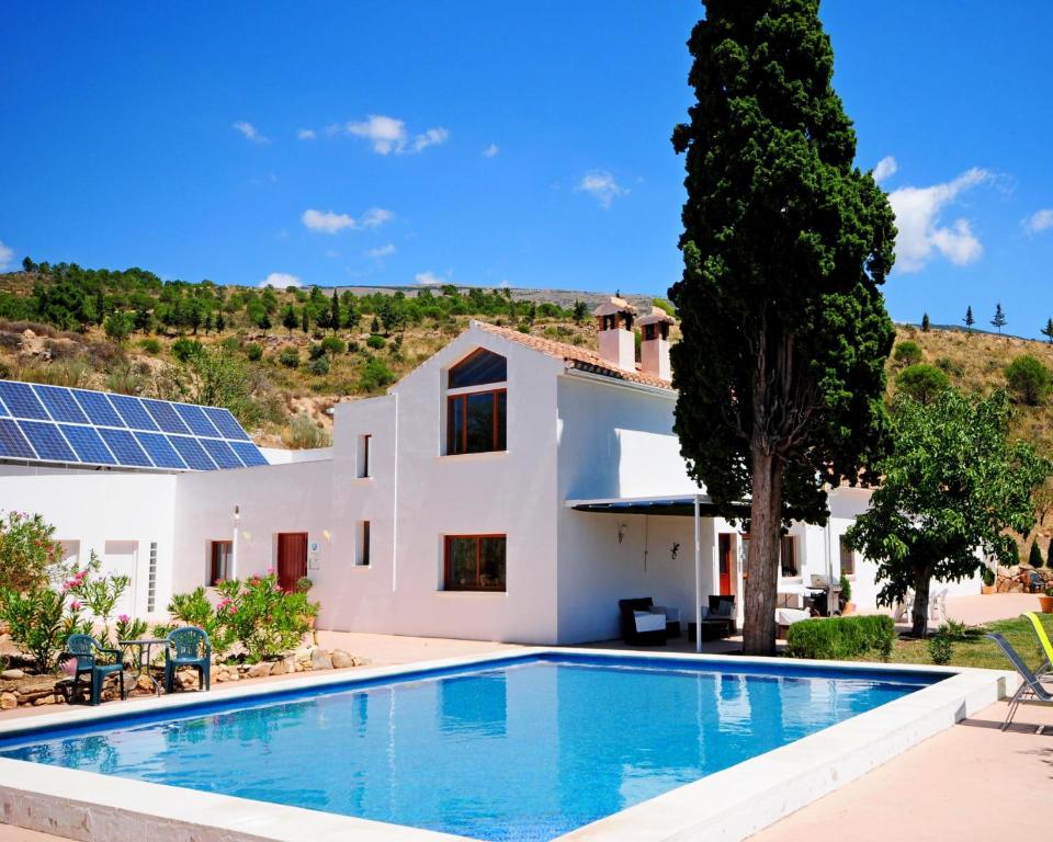 uma villa com piscina e uma casa com painéis solares em La Fuente Retreat em Lecrin