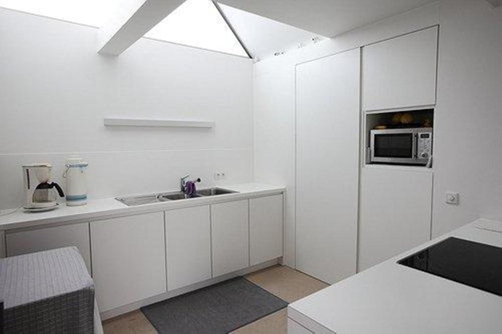 a white kitchen with a sink and a microwave at B&B 't Walleke in Bruges