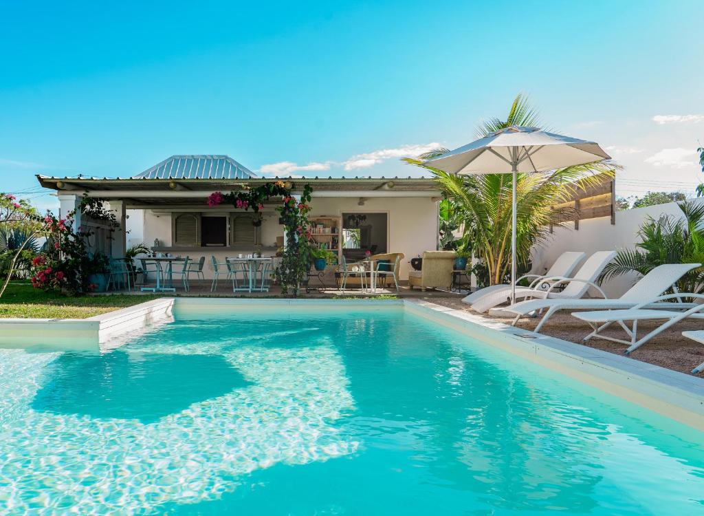 uma piscina com cadeiras e um guarda-sol ao lado de uma casa em Le Mandala Moris em Pointe aux Cannoniers