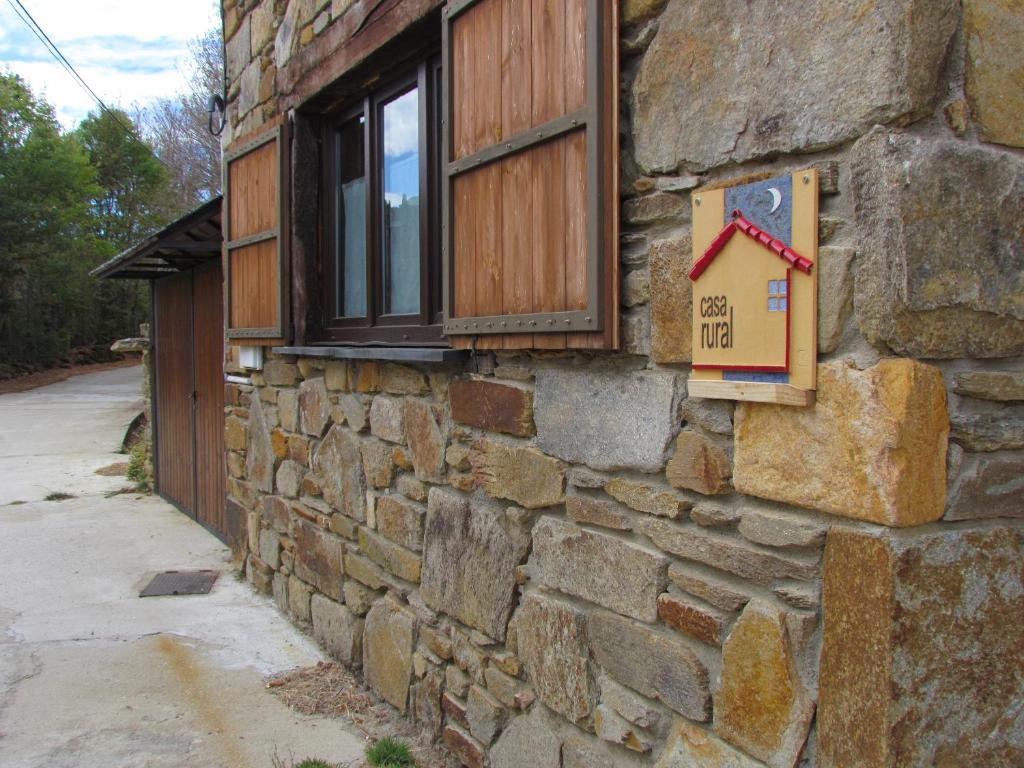 un edificio de piedra con una ventana y un cartel en él en CASA RURAL El Refugio del Poeta, en Triufé