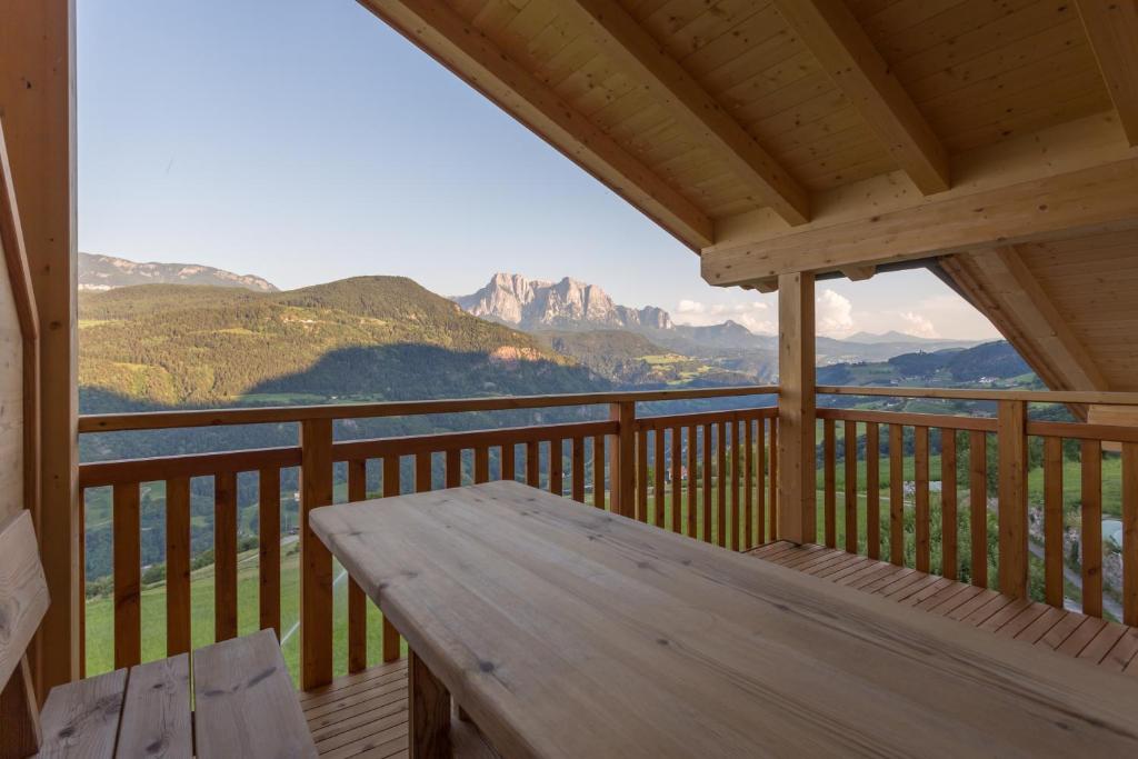 een houten veranda met een houten tafel op een balkon met bergen bij Frühaufhof in Barbiano
