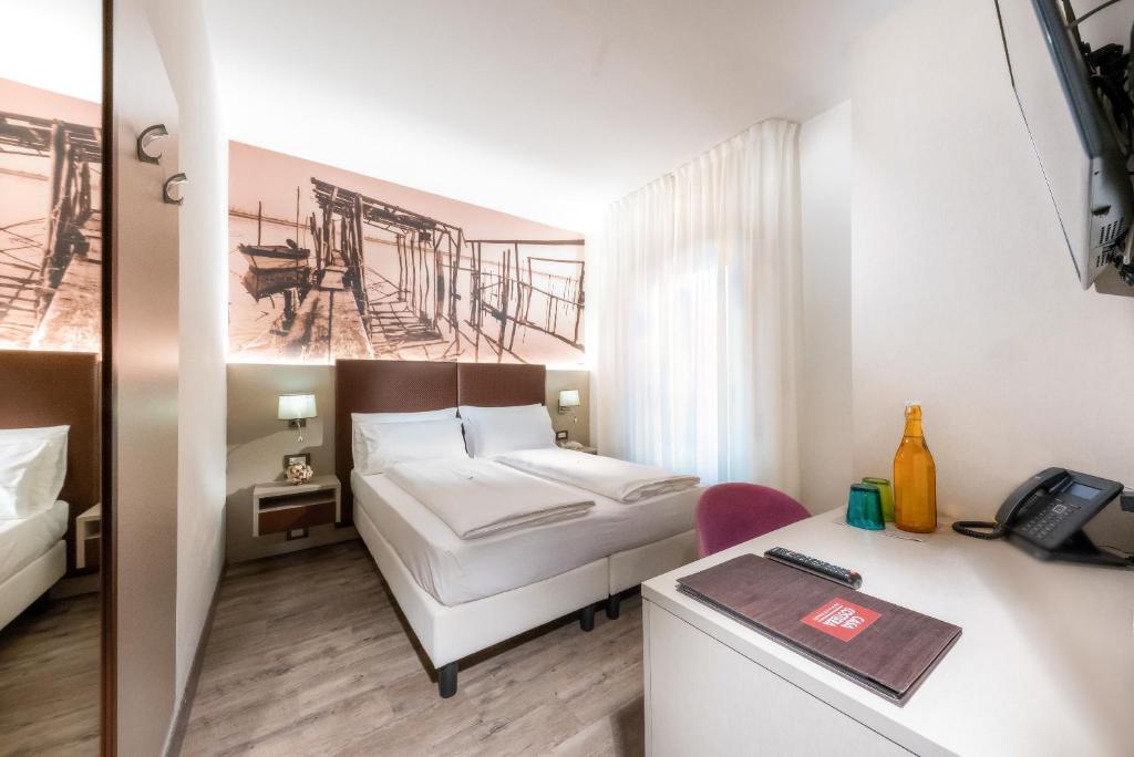 a hotel room with a bed and a desk at Hotel Casa Costiera in Caorle