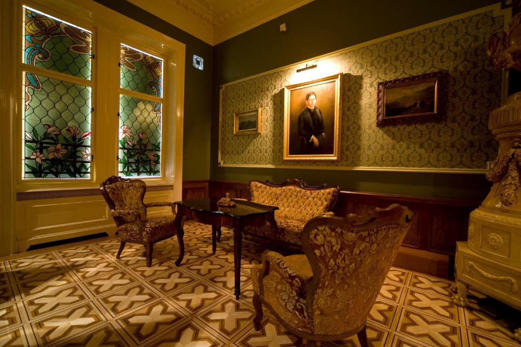 a living room with a table and chairs and a painting at Boutique Hotel Victoria Budapest in Budapest