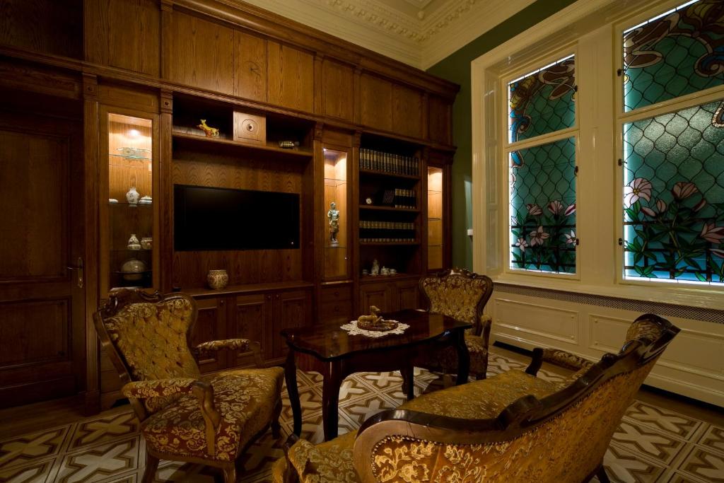a living room with a table and chairs and a television at Boutique Hotel Victoria Budapest in Budapest