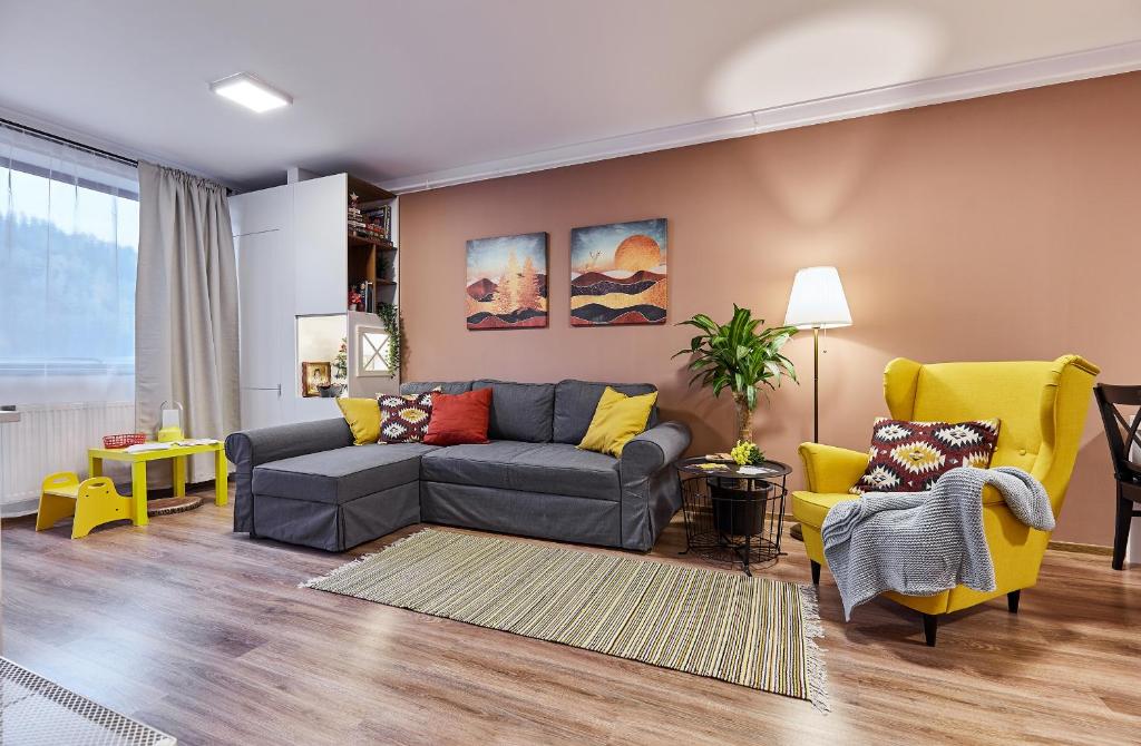 uma sala de estar com um sofá cinzento e cadeiras amarelas em Sinaia Q Marie Apartment em Sinaia
