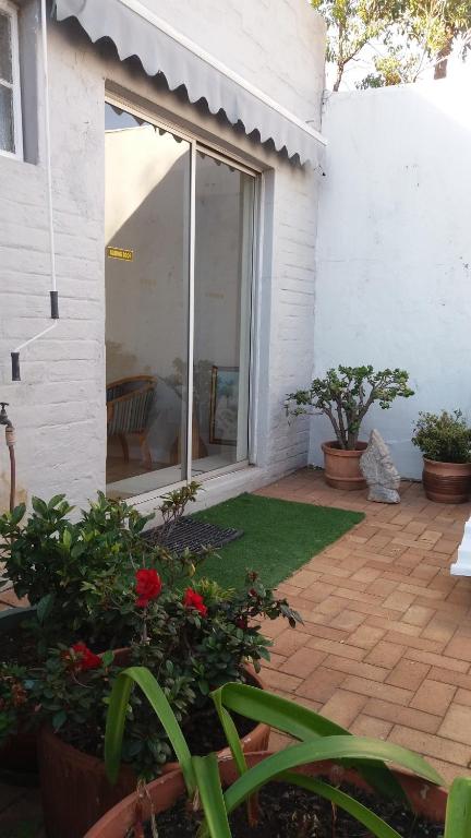 a house with a patio with red flowers and plants at "La Couronne" in Johannesburg