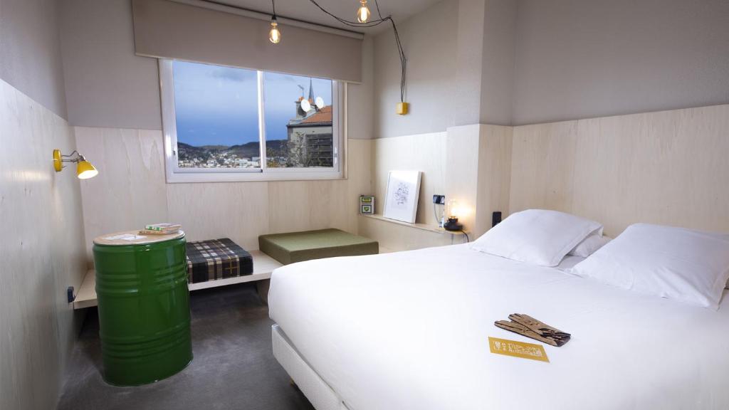 a bedroom with a large white bed and a window at ARTYSTER CLERMONT-FERRAND in Clermont-Ferrand