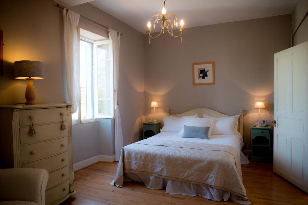 1 dormitorio con cama, ventana y lámpara de araña en Le Petit Cochon, en Valence-sur-Baïse