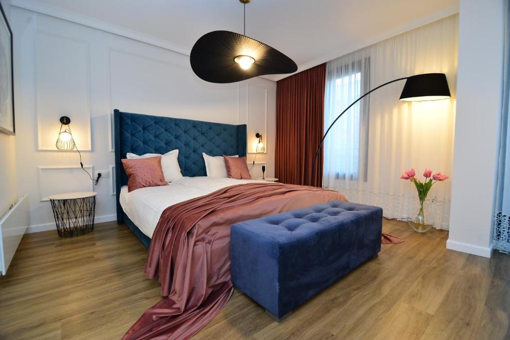 a bedroom with a large bed with a blue tufted headboard at Boutique Apartments Blagoevgrad in Blagoevgrad