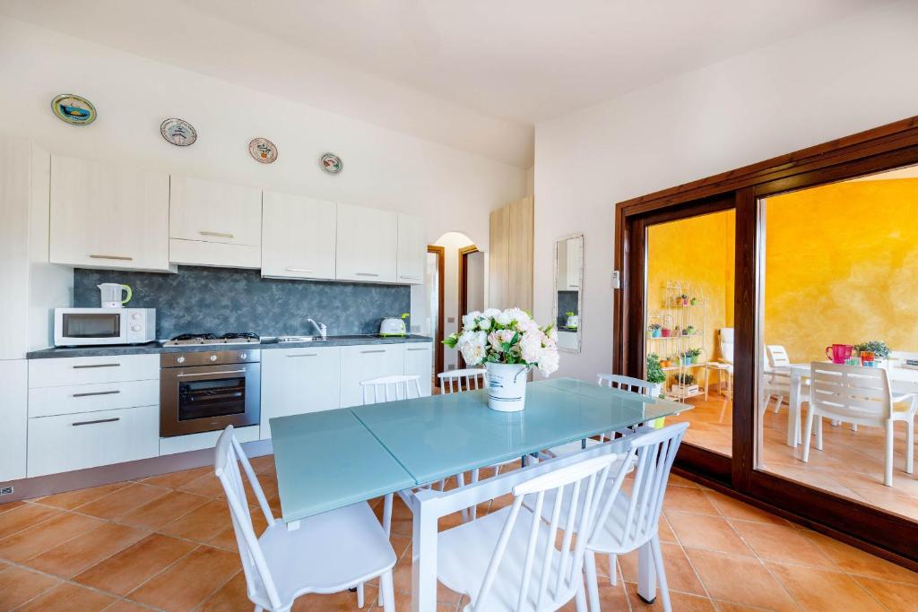 una cucina con tavolo blu e sedie bianche di Lu Maestrali Apartment a San Teodoro