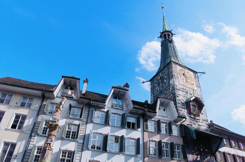 ein Gebäude mit einem Uhrturm darüber in der Unterkunft Hotel Roter Turm in Solothurn