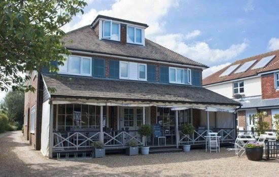 uma casa grande com janelas e cadeiras em frente em The Beach House em West Wittering