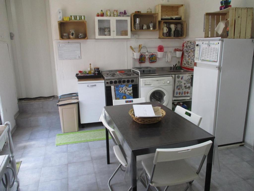 Il comprend une cuisine équipée d'une table et d'un réfrigérateur blanc. dans l'établissement Palazzo Ruisi, à Scordia