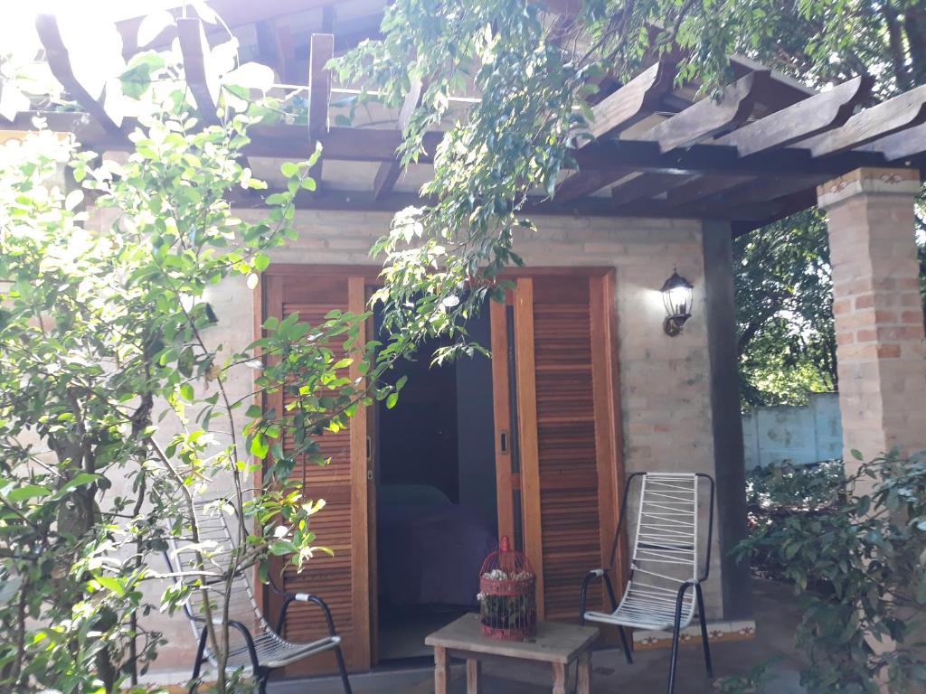 ein Haus mit zwei Stühlen, einer Tür und einem Tisch in der Unterkunft Casa Jabuticaba Refúgio e Hospedagem in São Miguel Arcanjo