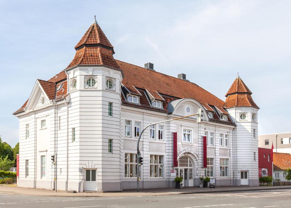 ein großes weißes Gebäude mit rotem Dach in der Unterkunft Hotel Alter Kreisbahnhof in Schleswig