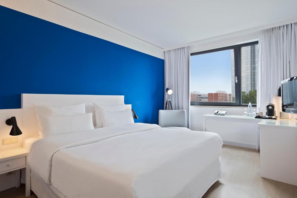 um quarto com uma cama branca e uma parede azul em Hotel Frankfurt Messe Affiliated by Meliá em Frankfurt