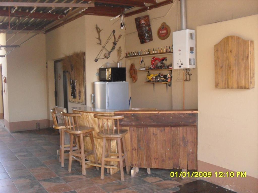 a kitchen with a bar with chairs and a refrigerator at Silvermoon in Nigel