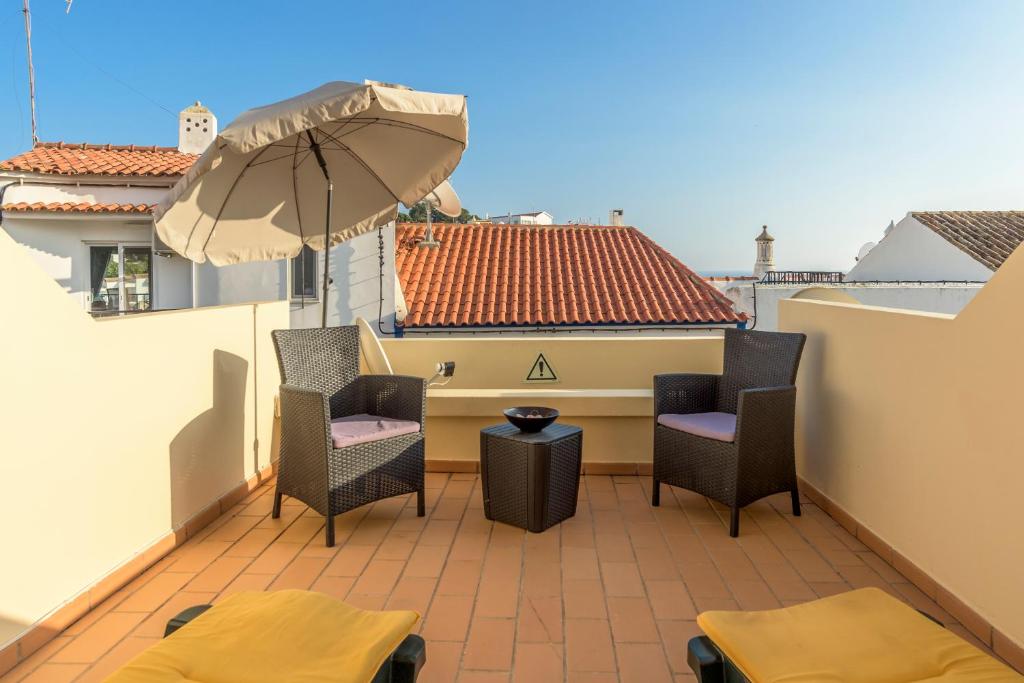 um pátio com cadeiras e um guarda-sol numa varanda em FLH Carvoeiro Beach Place with Terrace em Carvoeiro