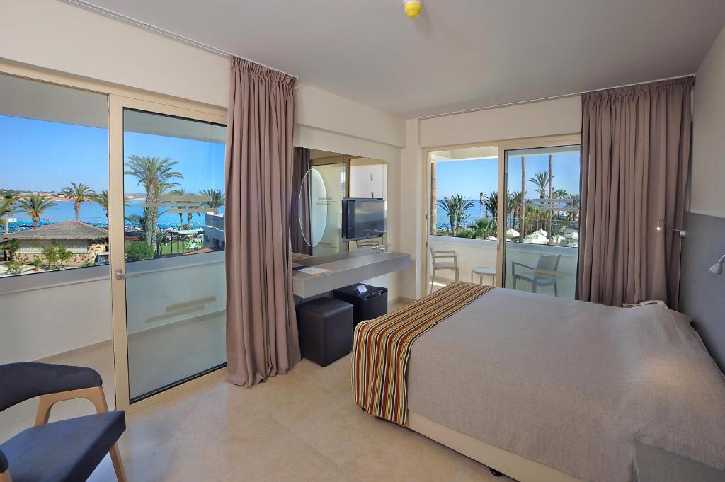a bedroom with a bed and a view of the ocean at Nelia Beach Hotel & Spa in Ayia Napa