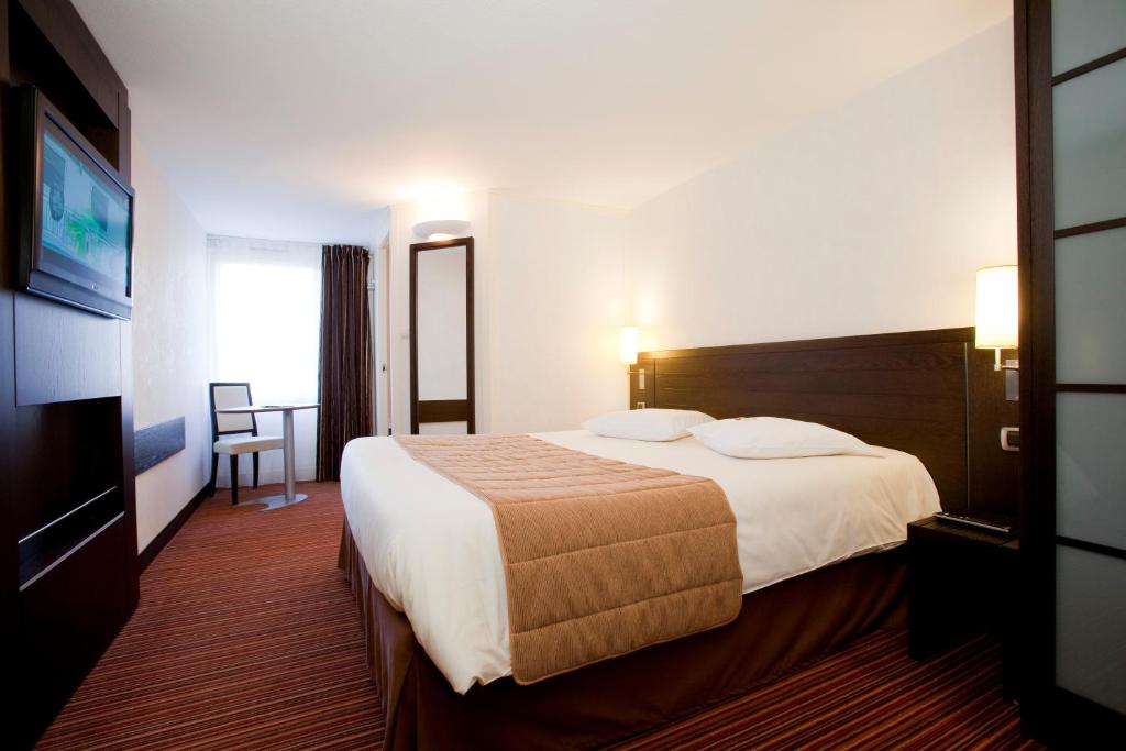 カルクフーにあるHôtel Inn Design Resto Novo Carquefouのベッドとテレビが備わるホテルルームです。
