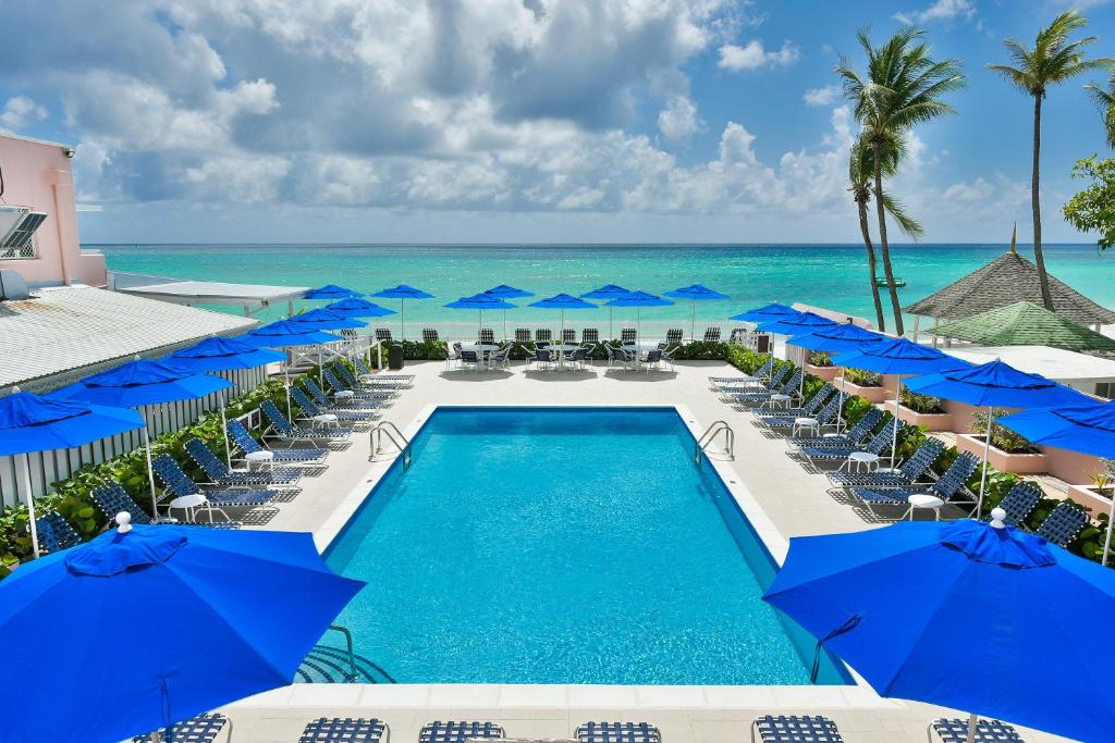 vistas a la piscina del complejo con sombrillas azules en Butterfly Beach Hotel en Christ Church