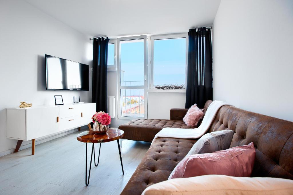 a living room with a couch and a tv at Apartament Wyzwolenia - Unique Apartments in Szczecin