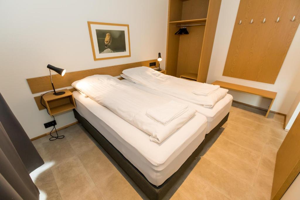 un grande letto bianco in una stanza con una lampada di Hrimland Apartments ad Akureyri